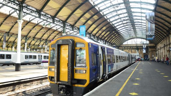 Train waits at an empty platform in a large station with a glass roof.