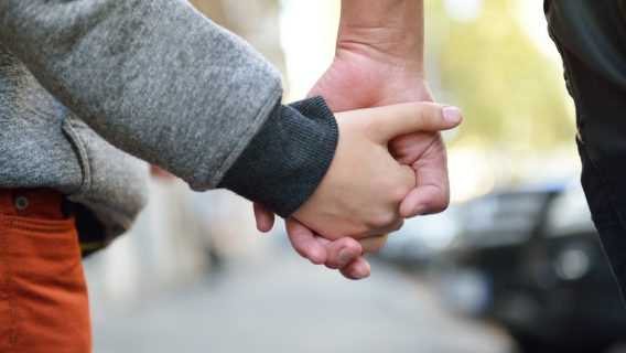 Zoomed in image of mother and child holding hands