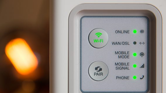 Close up of a panel on a wifi router, with green lights indicating that the wifi is online.