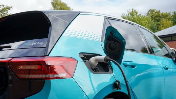 Bright blue electric car plugged into a charging point