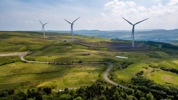 Aerial view of large wind turbines on a rural hillside in Wales