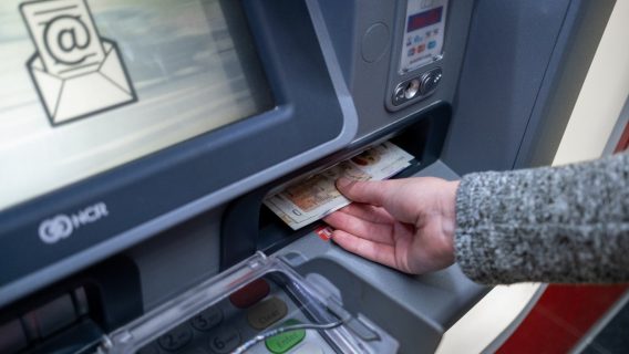 A hand taking cash from an ATM.