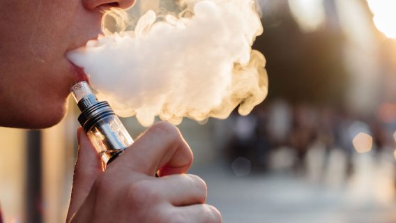 person using a vape,with smoke coming out of mouth