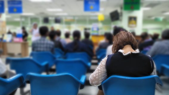young woman sits on a blue chair at the emergency room,